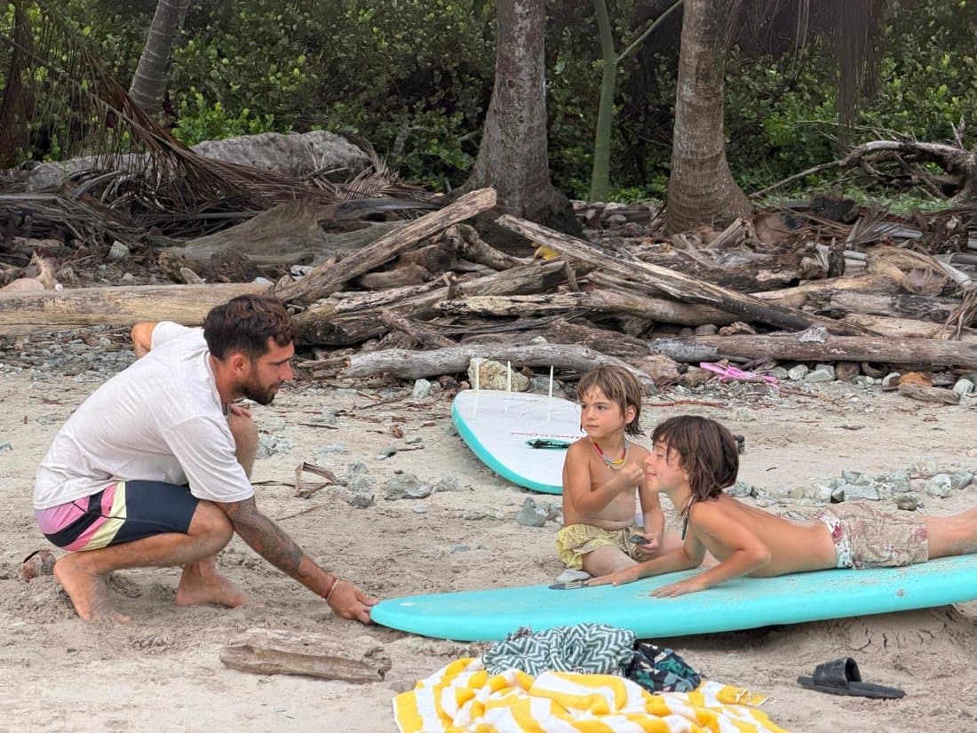 A coach teaching two kids on the sand